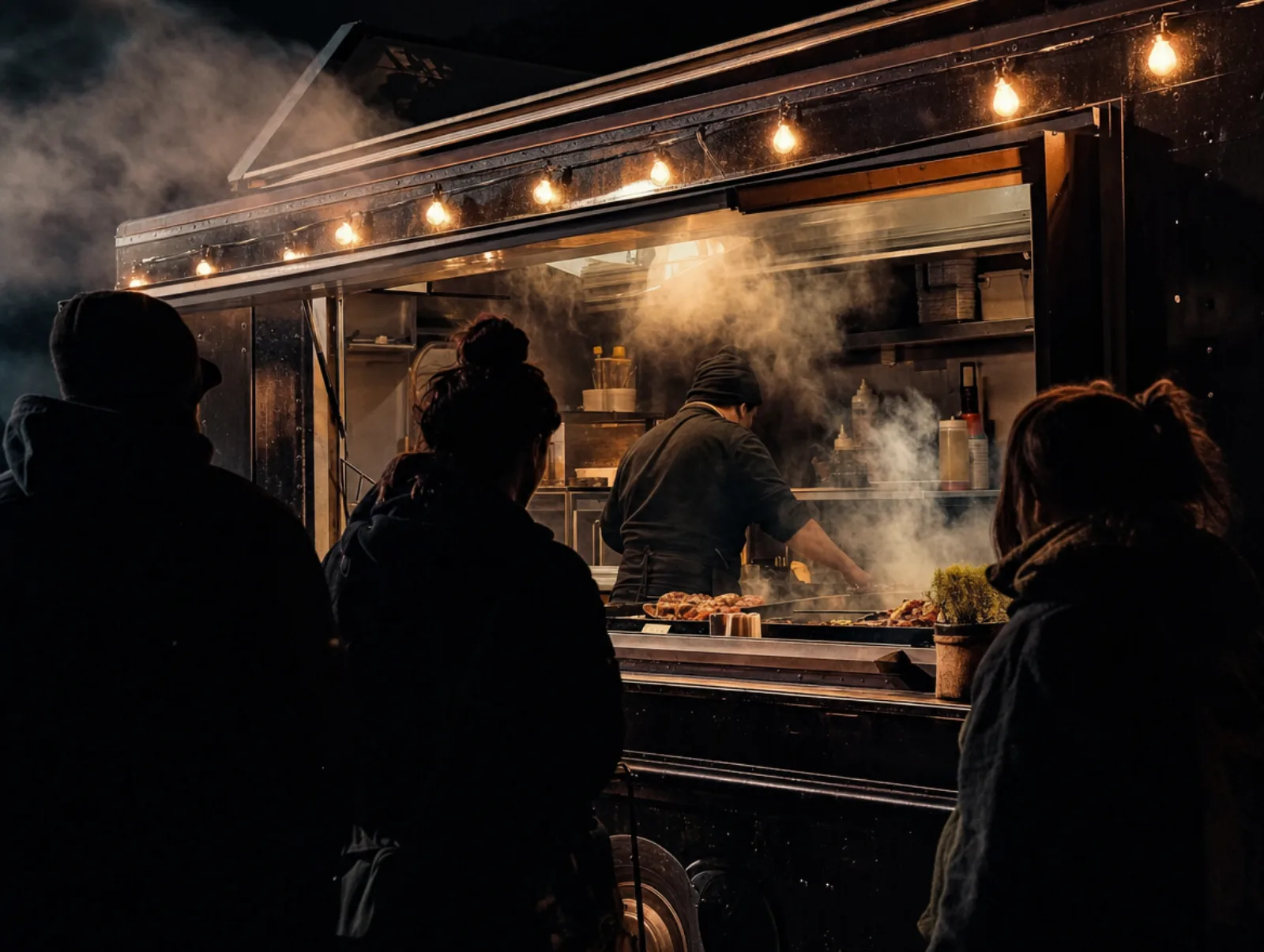Night service at the Rolling Ember BBQ truck window under string lights